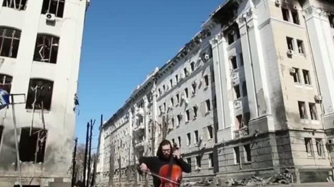 Житель Украины играет на фоне разбомбленных домов