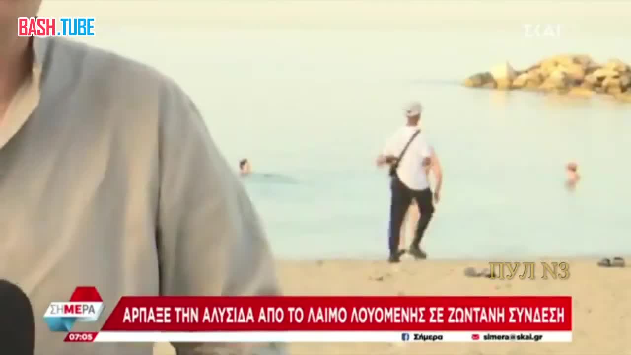 ⁣ В Греции во время прямого телевизионного включения с пляжа мигрант на заднем плане сорвал крестик с шеи пожилой женщины